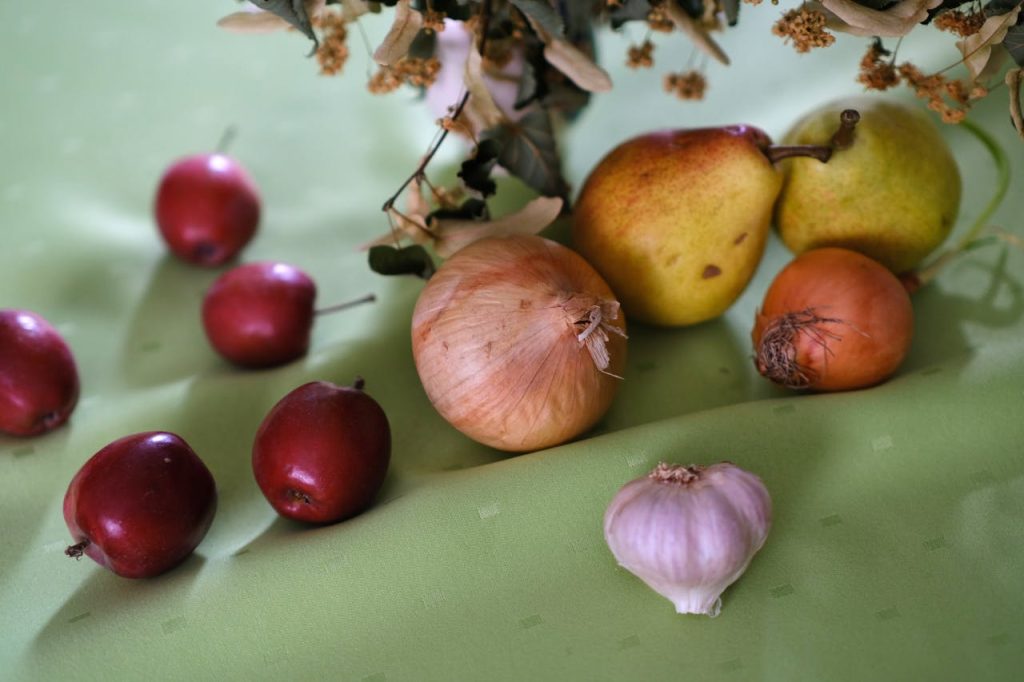 fresh-produce-still-life-with-pears-and-onions-34009265 Artistic arrangement of fruits and vegetables on a vibrant green surface.